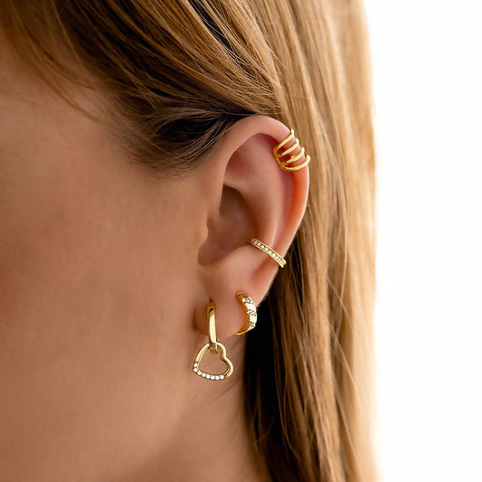 Frau mit goldenen Ohrringen und Ohrmanschette, Herzform, Glitzer, modischer Schmuck.
