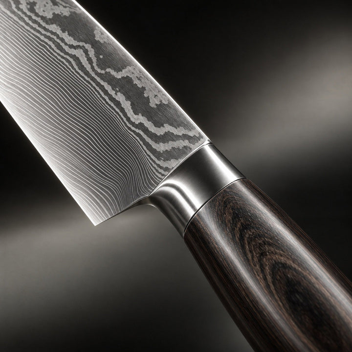 Nahaufnahme des Übergangs von der Klinge zum Holzgriff mit feiner Maserung im Stahl und metallischer Zwinge. 3