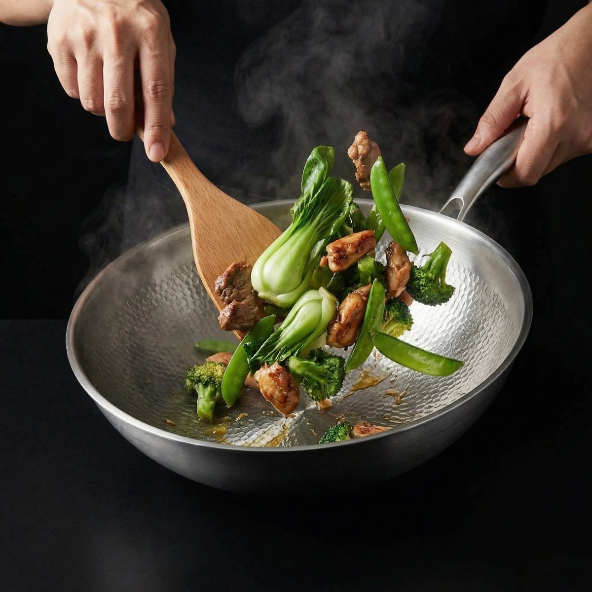 Zwei Hände wenden Pak Choi, Brokkoli, Zuckerschoten und Fleisch im Wok mit einem Holzwender. 7