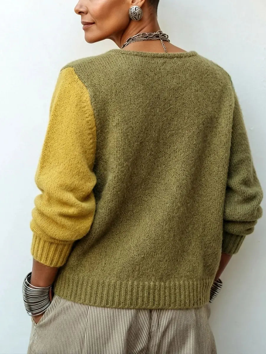 Rückansicht des Strickpullovers an einem Model: Rücken und linker Ärmel in Olivgrün, rechter Ärmel senfgelb, Rippbündchen am Saum. 2