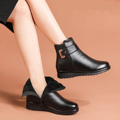 Schwarze Stiefeletten mit Keilsohle an übereinandergeschlagenen Beinen, ein Stiefel mit dunklem Futter und seitlichem 5