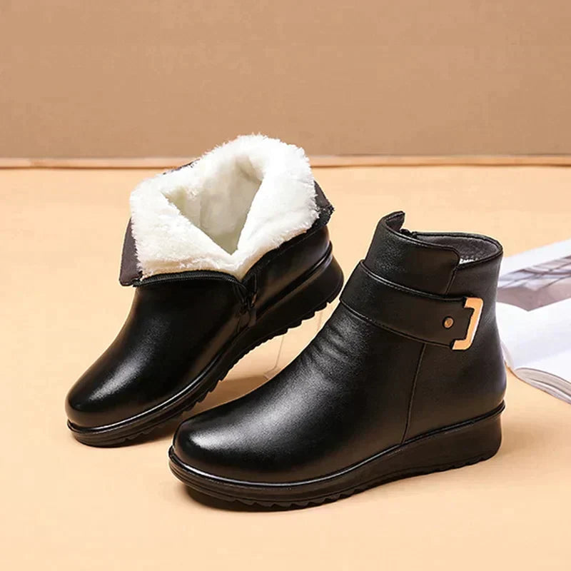 Schwarze Stiefeletten mit goldener Schnalle, ein Stiefel zeigt weißes, kuscheliges Plüschfutter und den seitlichen 3