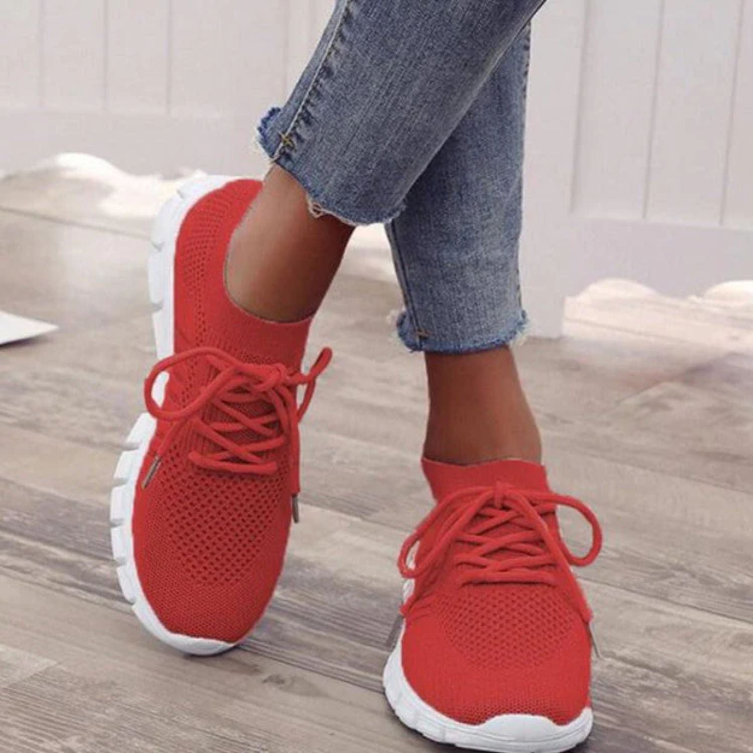Rote orthopädische Sneakers für Damen, atmungsaktiv, bequem, auf Holzboden.