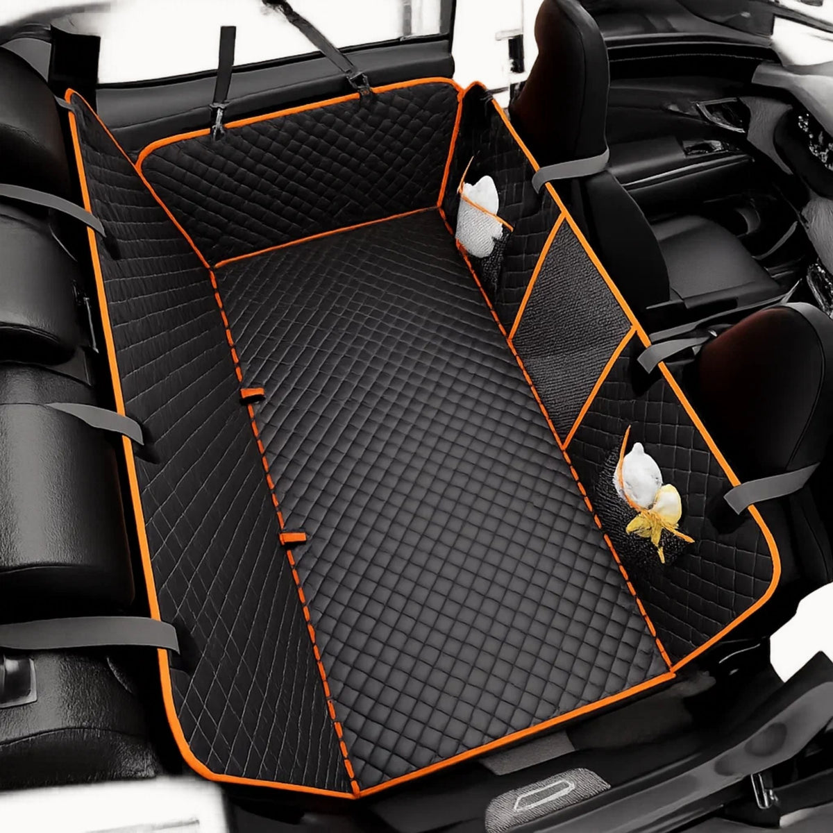 Schwarze Rautensteppung mit orangefarbener Einfassung auf der Rückbank, dazu Netztaschen mit Leckerlis und graue Befestigungsgurte. 8