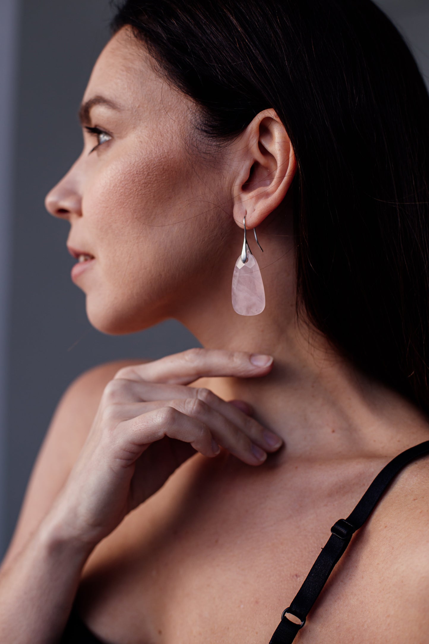 Frau mit rosa Ohrring, Silberhaken, Nahaufnahme, modisches Accessoire, eleganter Schmuck.