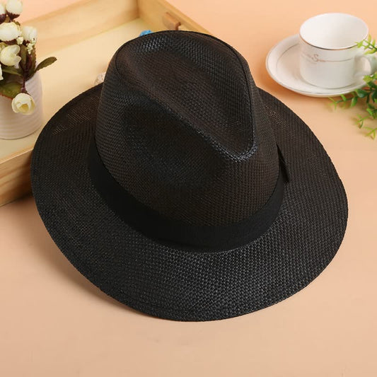 Schwarzer Fedora-Hut aus Stroh auf Tisch, stilvoller Sommerhut, Herrenmode-Accessoire.