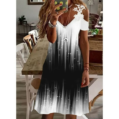 Frau in schwarz-weißem Sommerkleid mit Blumenmuster, V-Ausschnitt, schulterfrei, im Esszimmer.