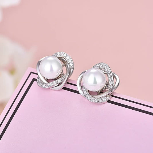 Silberne Ohrringe mit Perlen und Strasssteinen auf rosa Hintergrund, eleganter Schmuck.