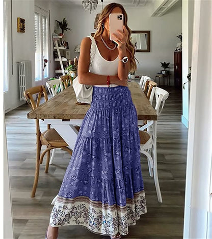Frau in weißem Top und blauem Maxirock mit Blumenmuster im modernen Esszimmer.