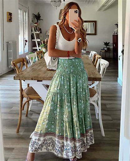 Frau in weißem Top und grünem Maxirock mit Blumenmuster, steht in modernem Esszimmer.