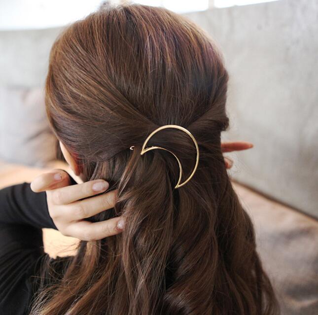 Frau mit braunem Haar trägt goldene Halbmond-Haarspange, elegantes Accessoire.