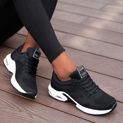Schwarze Damen-Sneaker, atmungsaktiv, Mesh, sportlich, bequem, modisch, auf Holzdeck.