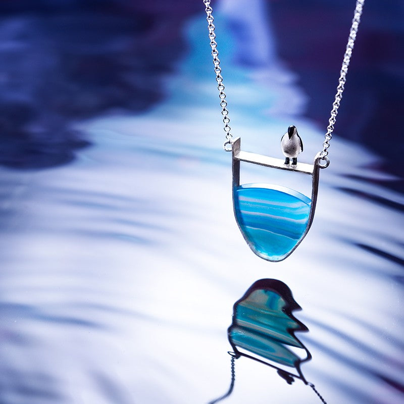 Silberkette mit blauem Achat-Anhänger und Vogelmotiv, eleganter Schmuck für Damen.