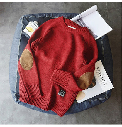 Roter Strickpullover mit braunen Ellbogen-Patches auf Jeanshocker, modisch, gemütlich.
