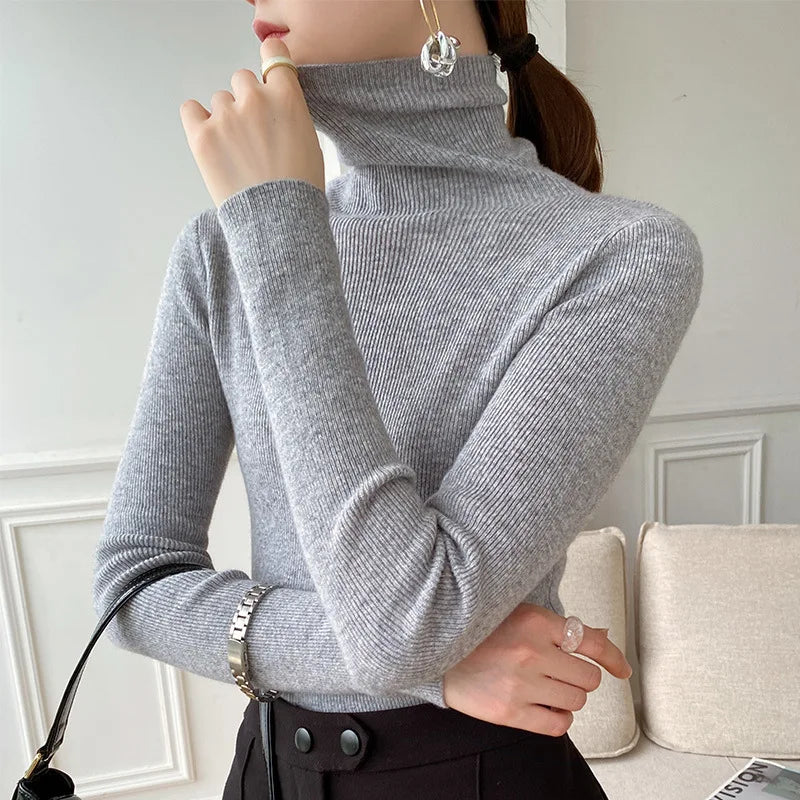 Grauer Rollkragenpullover am Model mit Zopf, schwarzem Rock und Tasche am Arm 7