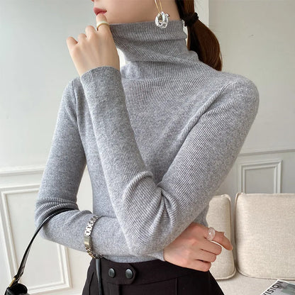 Grauer Rollkragenpullover am Model mit Zopf, schwarzem Rock und Tasche am Arm 7