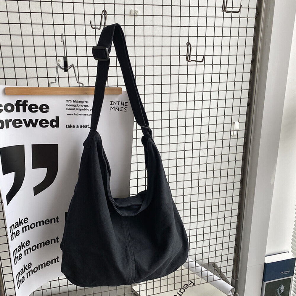 Schwarze Umhängetasche aus Stoff, lässig, modisch, hängend an einem Gitter, urbaner Stil.