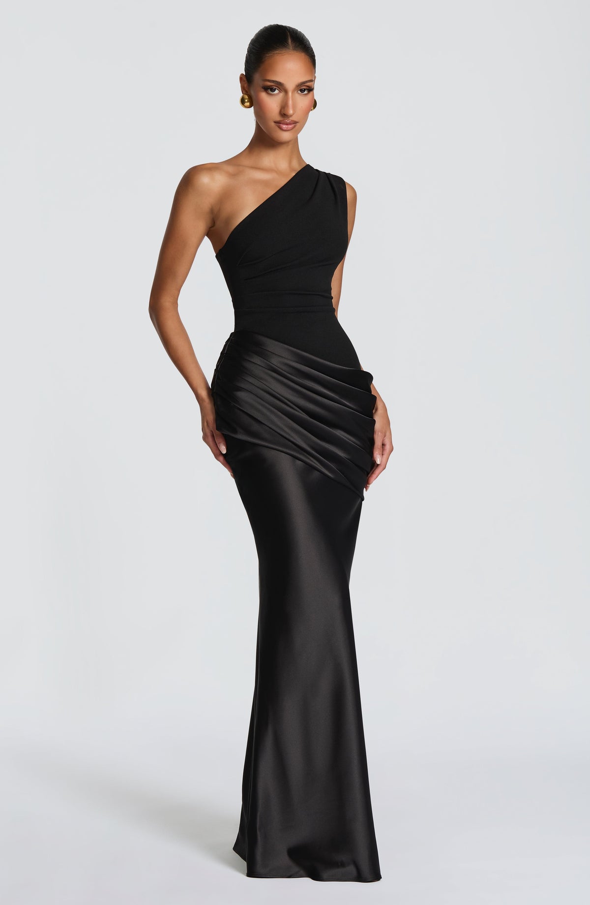 Schwarzes Maxikleid mit asymmetrischem Ausschnitt in Dreiviertelansicht, Model mit goldenen Ohrringen vor hellgrauem Hintergrund. 22
