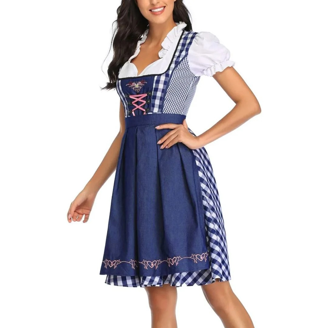 Dirndl in Marineblau mit blau-weiß kariertem Oberteil, bestickter Schürze und rosa Schnürung, Model mit Hand an der Hüfte. 6