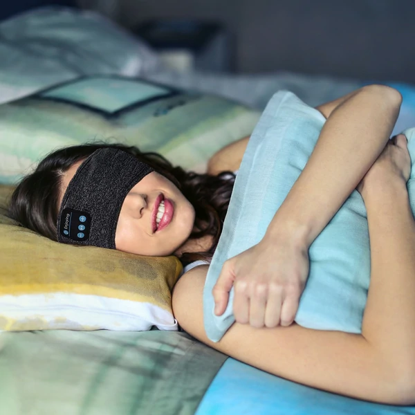 Frau trägt schwarzes Schlafband im Bett, Schlafmaske, Entspannung, Schlafhilfe, Komfort.