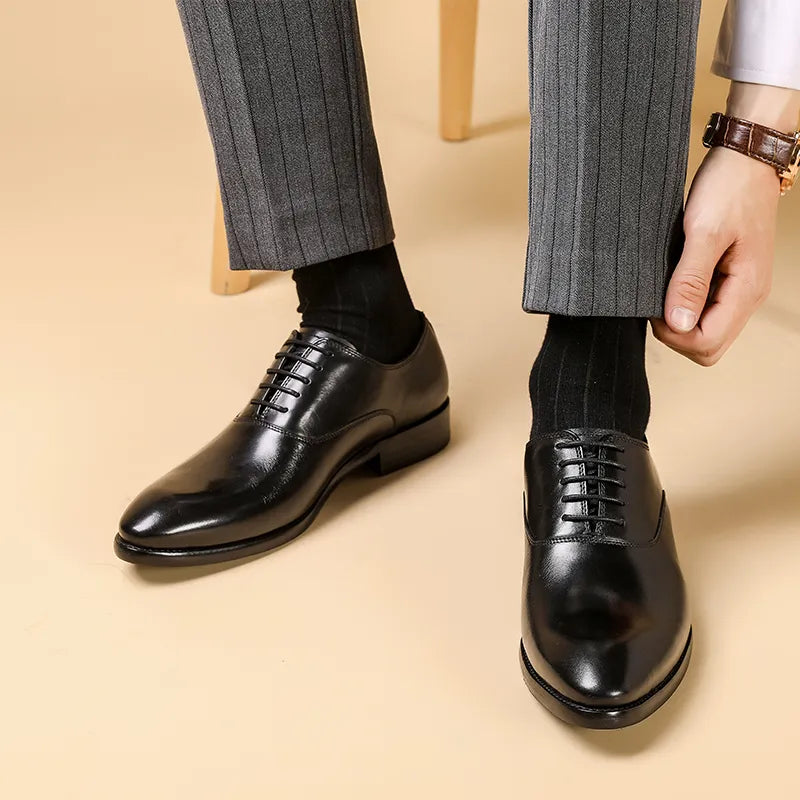 Schwarze, glänzende Schnürschuhe aus Leder, getragen zu grauer Nadelstreifenhose und schwarzen Socken, Mann richtet die 1