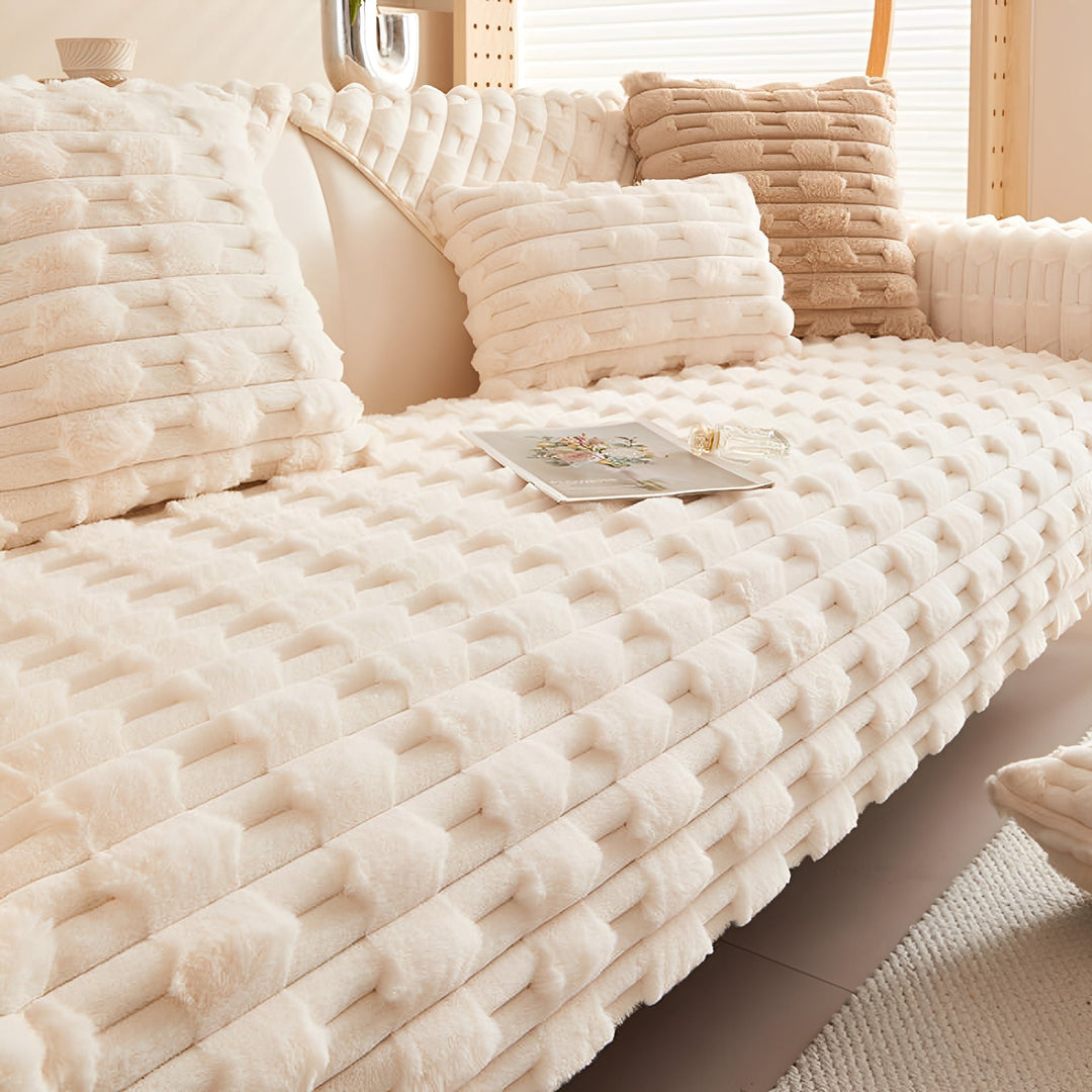 Cremeweiße Plüschdecke mit erhabenem Muster auf einem Sofa, mit passenden Kissen, einem aufgeschlagenen Heft und einem Fläschchen. 8