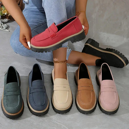 Loafer in sechs Farben im Überblick, ein roter Schuh wird in der Hand gehalten, daneben grün, blau, beige, braun, rosa und schwarz. 2
