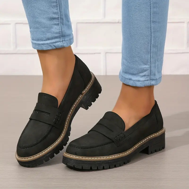 Schwarze Loafer mit dicker Profilsohle und heller Naht an den Füßen, getragen zu hellblauer Jeans. 6