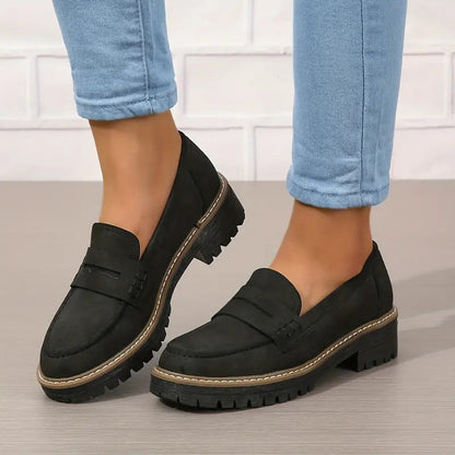 Schwarze Loafer mit dicker Profilsohle und heller Naht an den Füßen, getragen zu hellblauer Jeans. 6