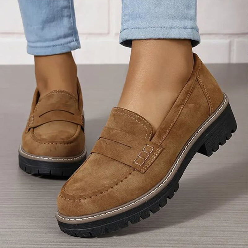 Braune Wildleder-Loafer in Nahaufnahme am Fuß, mit heller Kontrastnaht, Zierlasche und kräftiger Profilsohle, dazu hellblaue Jeans. 5