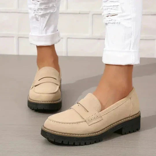 Beige Loafer an den Füßen einer Trägerin mit weißer Jeans, Seitenansicht mit schwarzer Profilsohle. 7