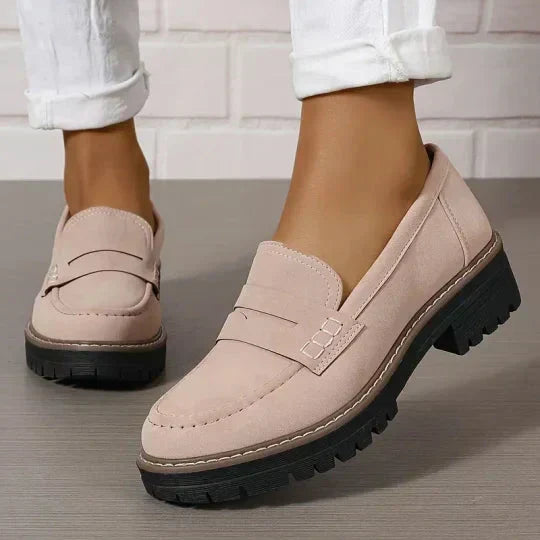 Rosé-beige Loafer mit Zierlasche und schwarzer Plateausohle, getragen zu weißer, umgeschlagener Hose, ein Fuß leicht angehoben. 8