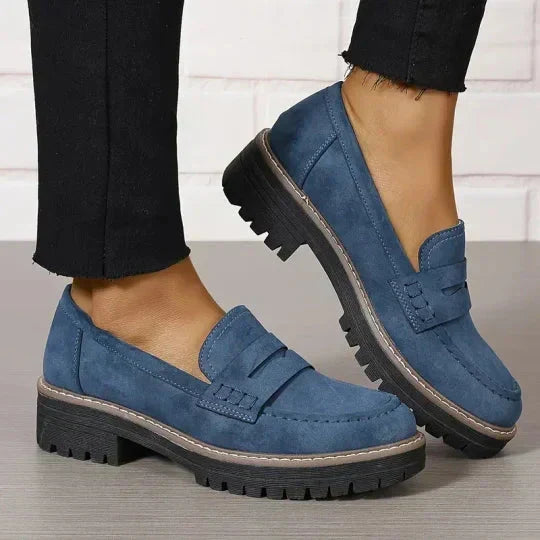 Blaue Loafer mit dicker schwarzer Profilsohle an den Füßen, kombiniert mit schwarzer Hose mit ausgefranstem Saum. 9