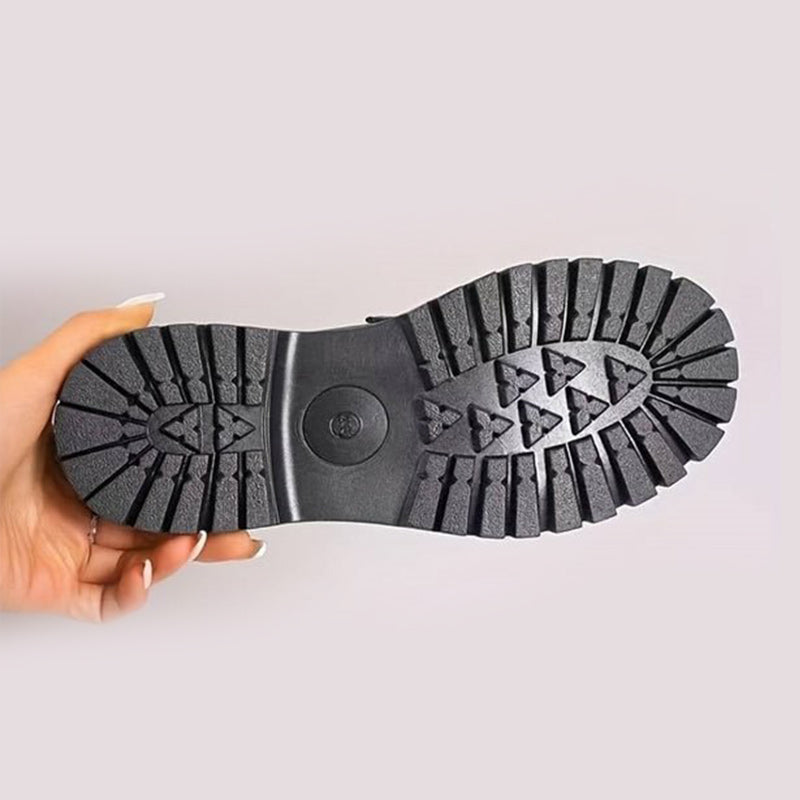 Schuhsohle von unten in der Hand gehalten, schwarze Gummisohle mit tiefem Stollenprofil für guten Halt. 10