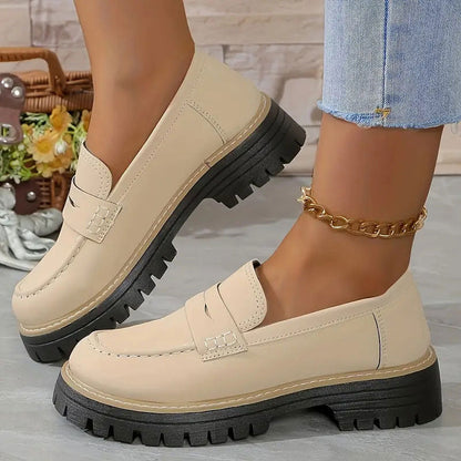 Beige Loafer in glatter Optik mit dicker schwarzer Profilsohle an den Füßen, mit goldener Fußkette. 14