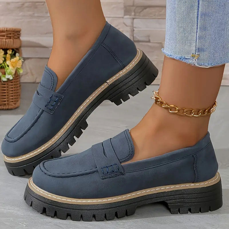 Blaue Loafer mit Plateausohle und hellem Zierrand an den Füßen, dazu goldene Fußkette und Jeans. 16