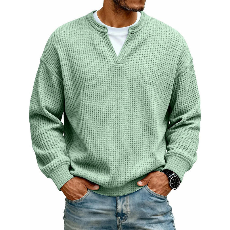 Frontansicht des Oberteils in hellem Grün am Model, mit weißem Shirt unter dem V-Ausschnitt, Hände in den Jeanstaschen. 10