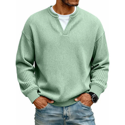 Frontansicht des Oberteils in hellem Grün am Model, mit weißem Shirt unter dem V-Ausschnitt, Hände in den Jeanstaschen. 10