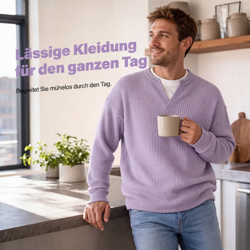 Lächelnder Mann im fliederfarbenen Waffelstrick-Oberteil lehnt in einer hellen Küche an der Arbeitsplatte und hält eine Tasse. 5