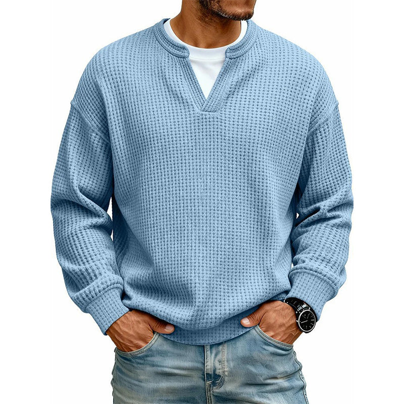 Frontansicht des Oberteils in hellem Blau am Model, mit weißem Shirt unter dem V-Ausschnitt, Hände in den Jeanstaschen. 12