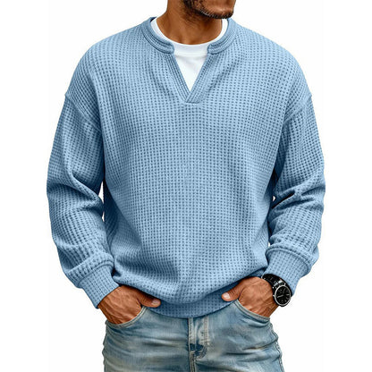 Frontansicht des Oberteils in hellem Blau am Model, mit weißem Shirt unter dem V-Ausschnitt, Hände in den Jeanstaschen. 12