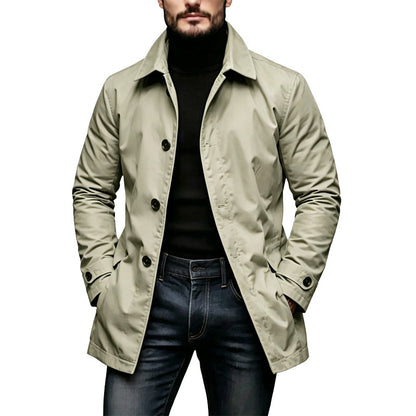 Mantel in hellem Beige-Grün an einem Model, offen getragen über schwarzem Rollkragen und Jeans, mit Riegeln an den Ärmeln. 3
