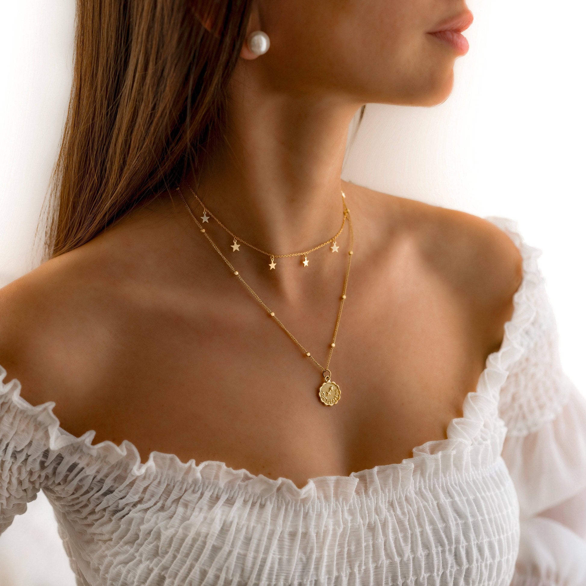Frau mit zweilagiger Sternenhalskette in Gold, eleganter Schmuck, modisches Accessoire.