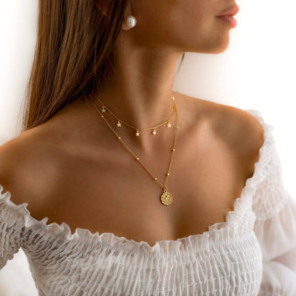 Frau mit zweilagiger Sternenhalskette in Gold, eleganter Schmuck, modisches Accessoire.