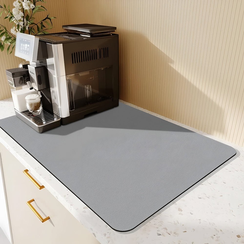 Hellgraue Unterlage auf einer Terrazzo-Arbeitsplatte unter einem Kaffeevollautomaten mit Touchdisplay, daneben eine Pflanze und eine gestreifte Wand. 8