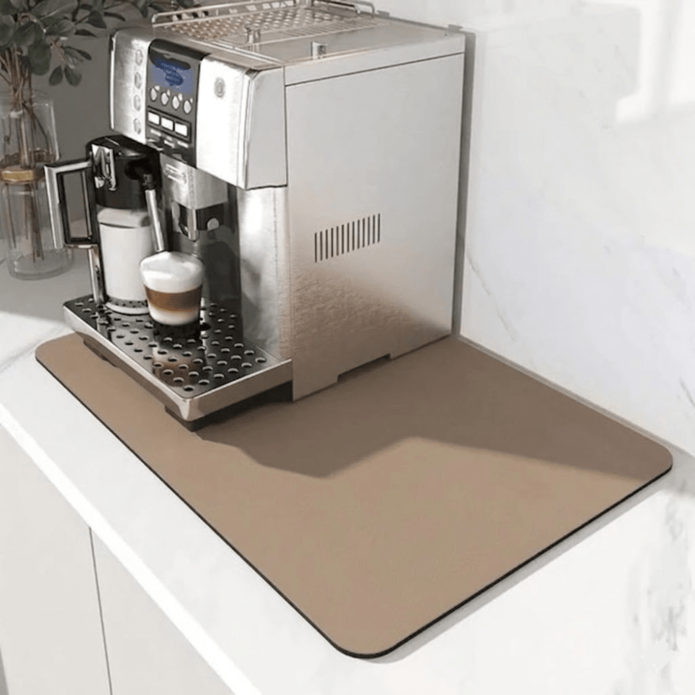 Hellbraune, beige Unterlage unter einem Kaffeevollautomaten, der einen Milchkaffee zubereitet, auf weißer Marmor-Arbeitsplatte. 7