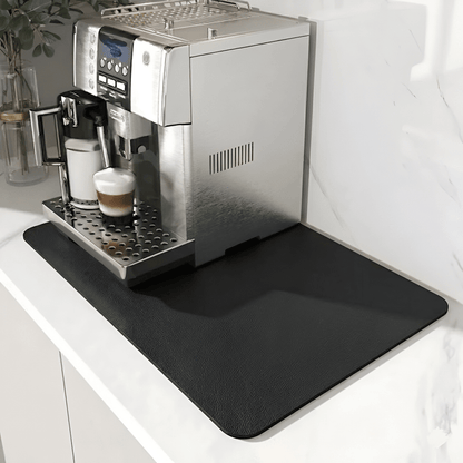 Schwarze Unterlage mit leicht genarbter Oberfläche unter einem Kaffeevollautomaten auf heller Marmor-Arbeitsplatte. 9