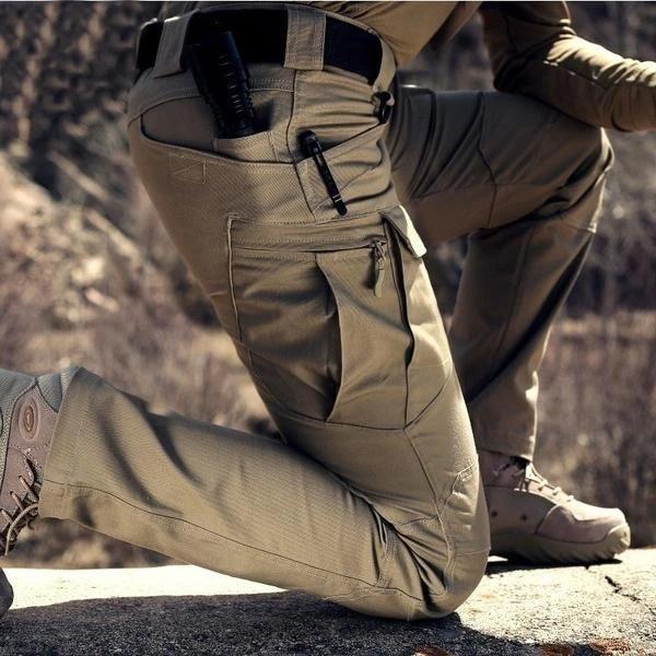 Nahaufnahme der khakifarbenen Hose am knienden Träger im Freien, Oberschenkeltasche mit Reißverschluss und Stift in der 2