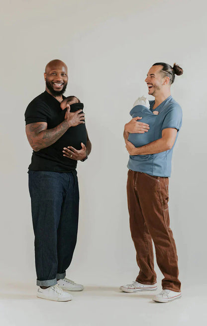 Zwei Männer tragen Babytragen-Shirts, schwarz und blau, lächelnd, lässige Kleidung.
