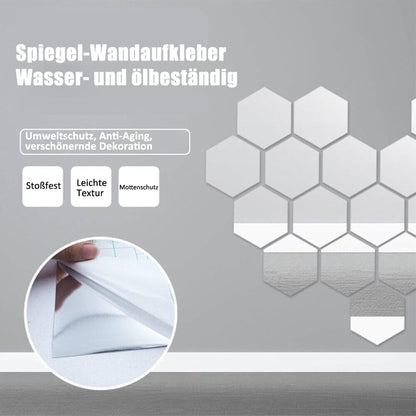 Sechseckige Spiegelaufkleber an einer grauen Wand, in einem Kreis ein Finger, der die Trägerschicht von der Spiegelfläche abzieht. 4